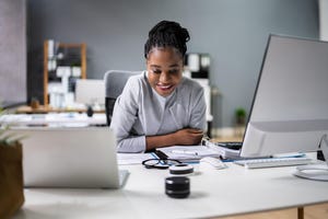 image of woman at a desk with two laptops