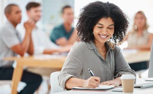 A businesswoman takes notes during a meeting, workshop, or training seminar in the office.