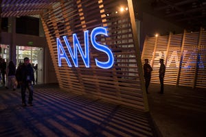 Conference attendees walk past signage for Amazon Web Services.