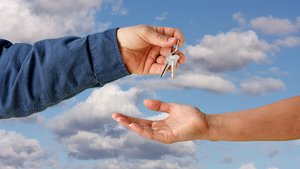 person handing keys to another person with clouds in background